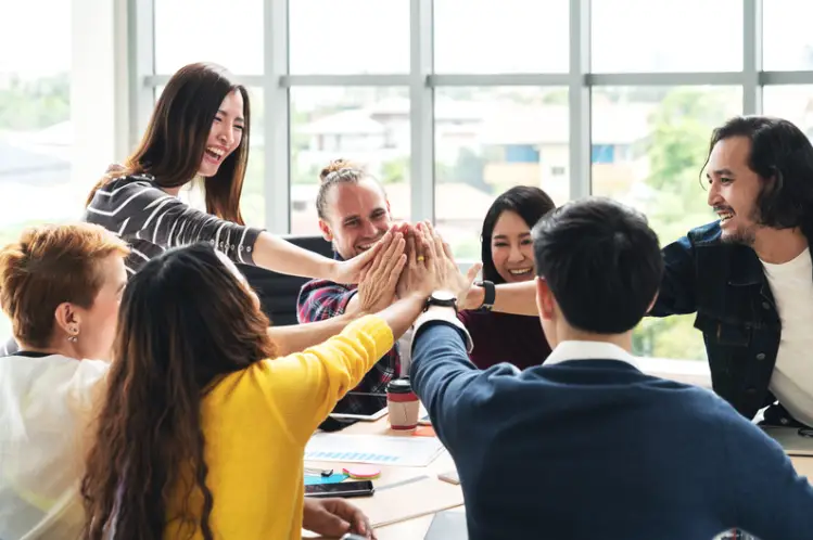 a group of people around a table high fiving