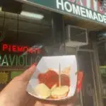 a close up of a person holding a donut in front of a building