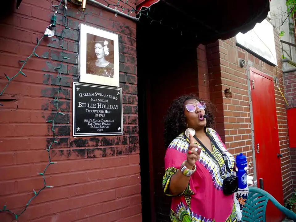 Introducing our Social Impact Experience: Sustainable Harlem Tour | Like A Local Tours a woman standing in front of a brick wall talking on a cell phone