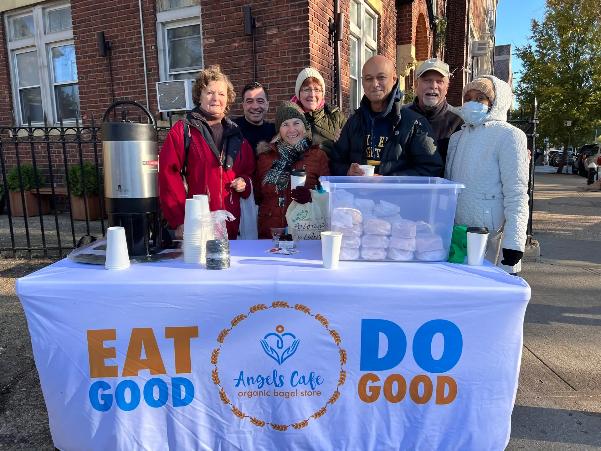 group of people behind a table outside offering free breakfast and coffee