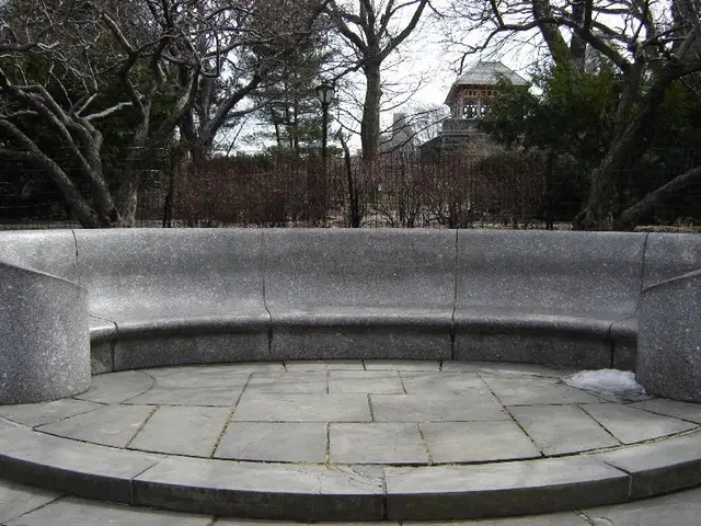 an empty park bench next to a brick wall