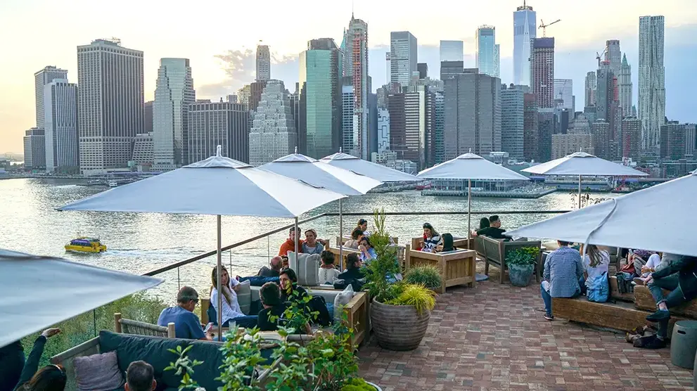 a group of people sitting on a rooftop with views of NYC in the background