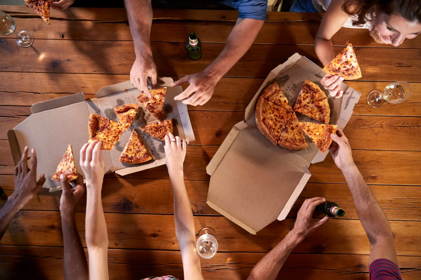 various hands reaching for pizza