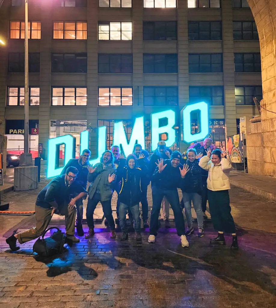 a group of people standing in front of the DUMBO sign