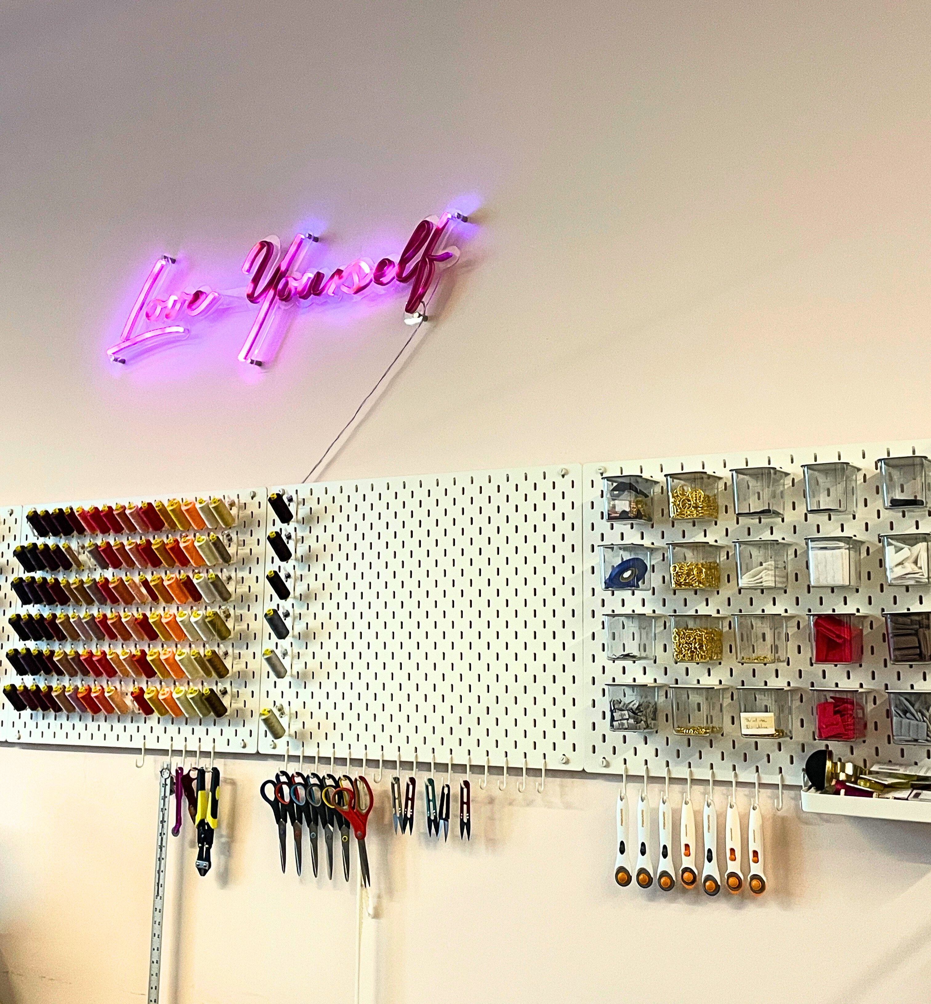 threads and lace trims at a lingerie workshop with a love yourself neon sign