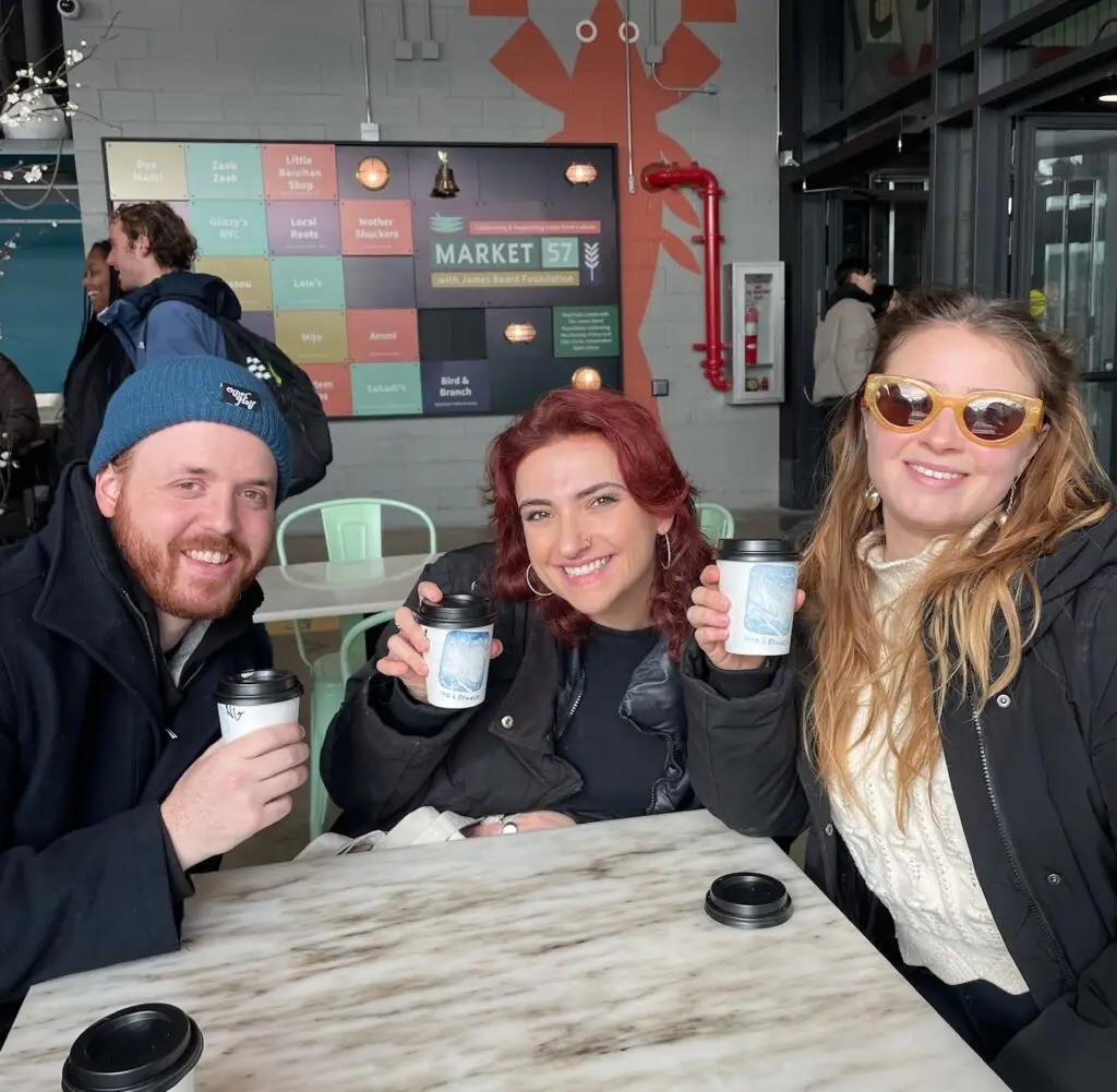 a group of people sitting around a table drinking coffee