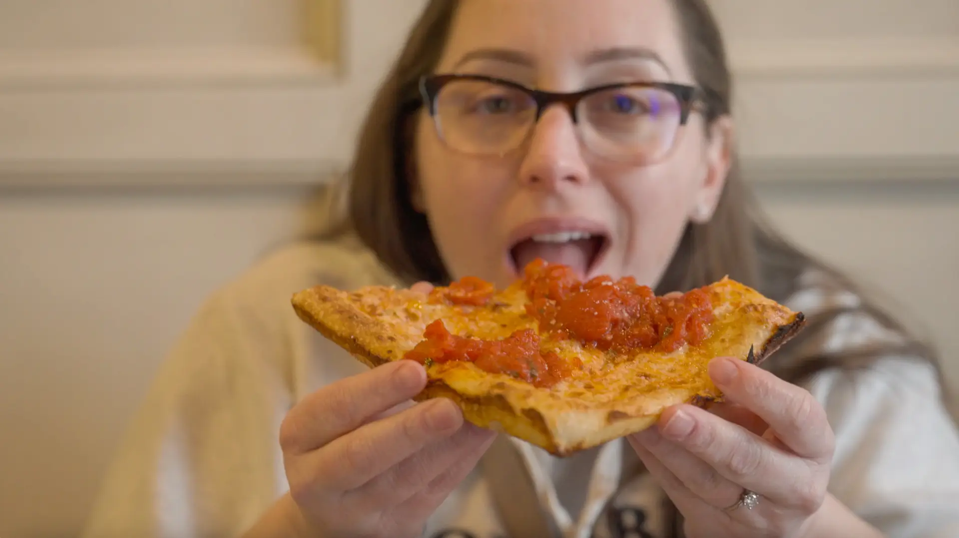 woman biting into a slice of pizza