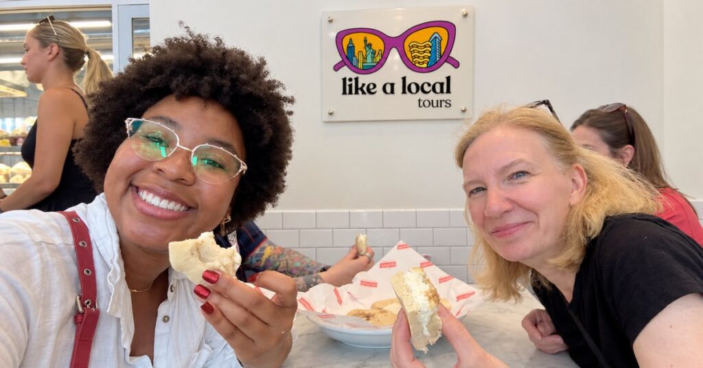 Guests tasting Lower East Side bagels beside the Like A Local Tours sign