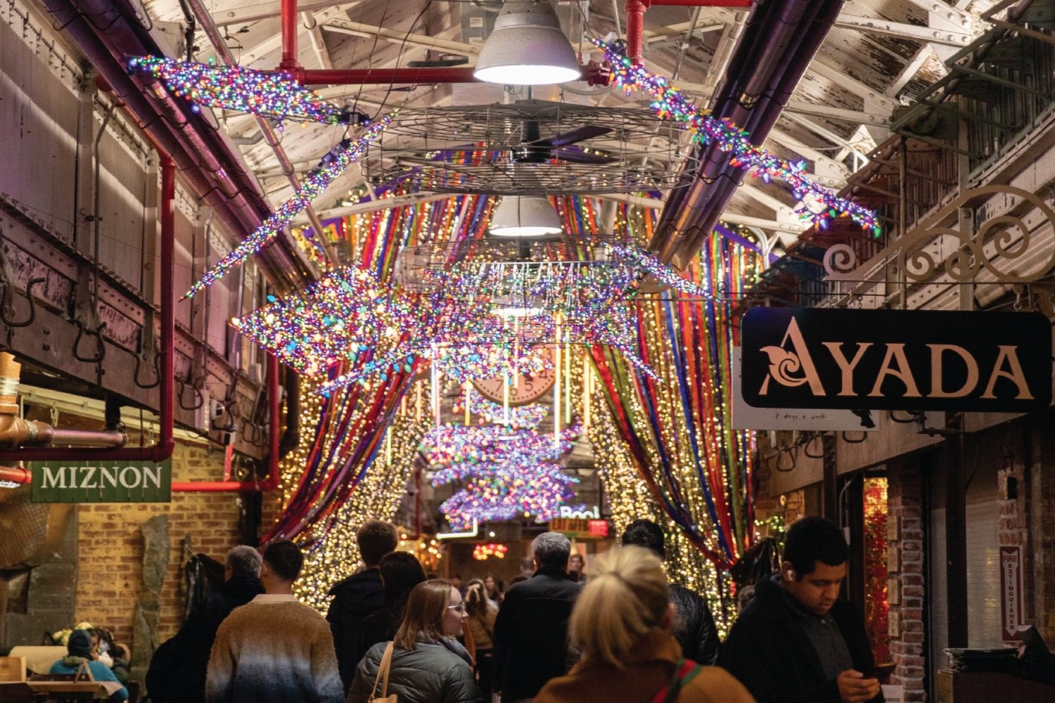 a group of people walking in front of a store during Holiday lights