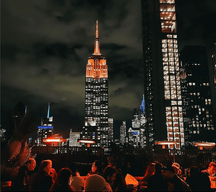 a lit up city at night with Empire State Building in the background