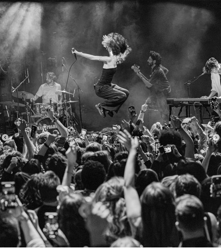 a group of people watching a band on stage in front of a crowd